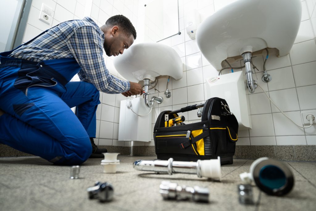 plumber fixing pipe in bathroom. plumbing maintenance